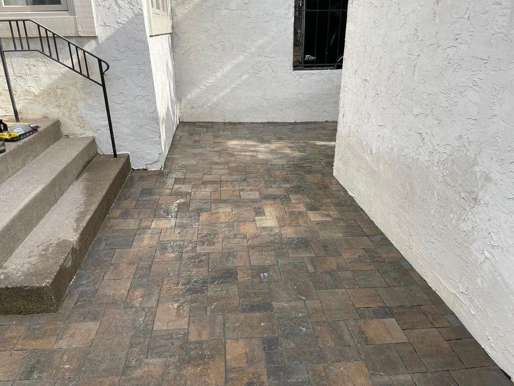Paved outdoor area next to a building with decorative stone flooring and stairs.